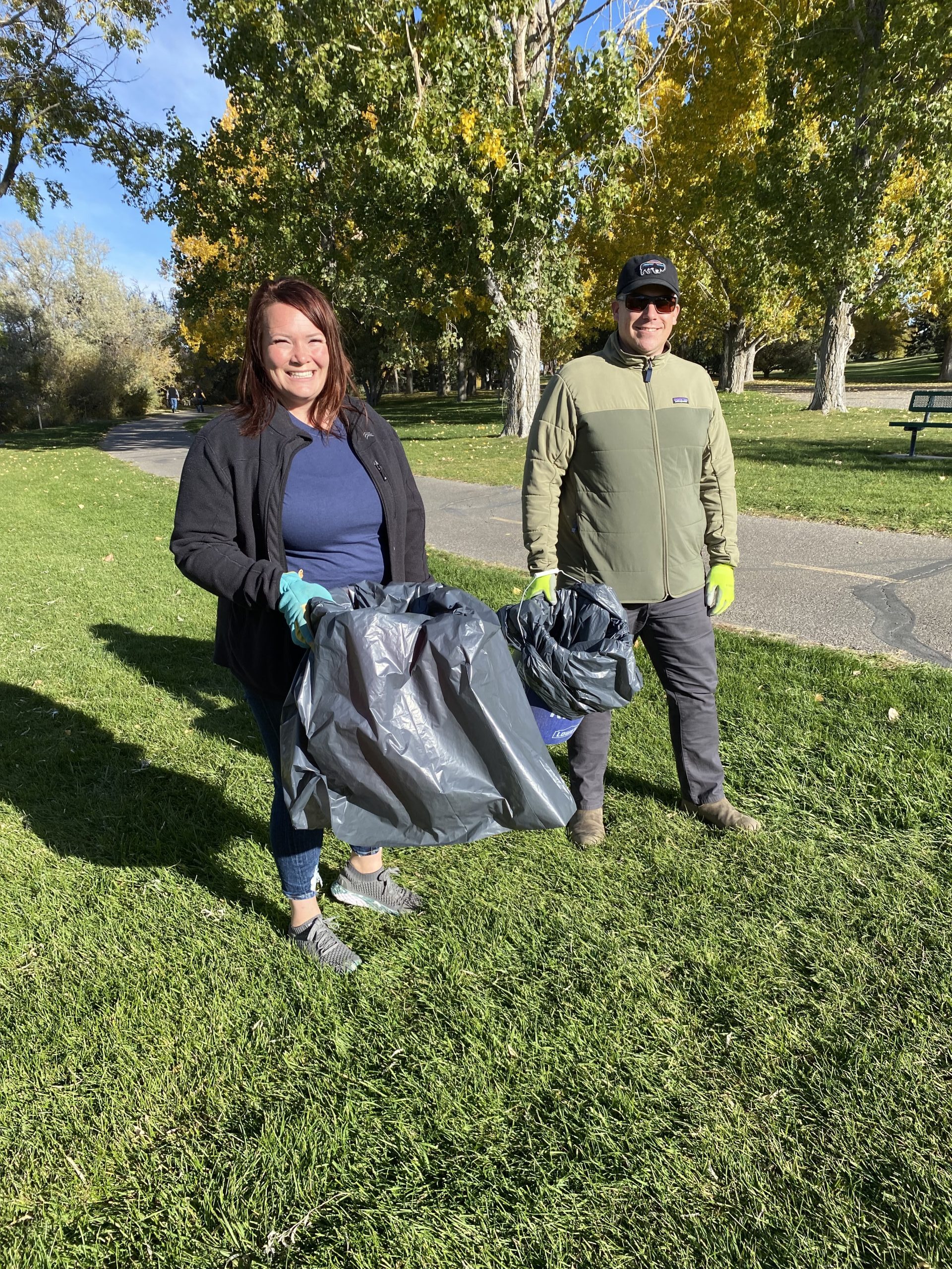 2 people holding trash can for clean up