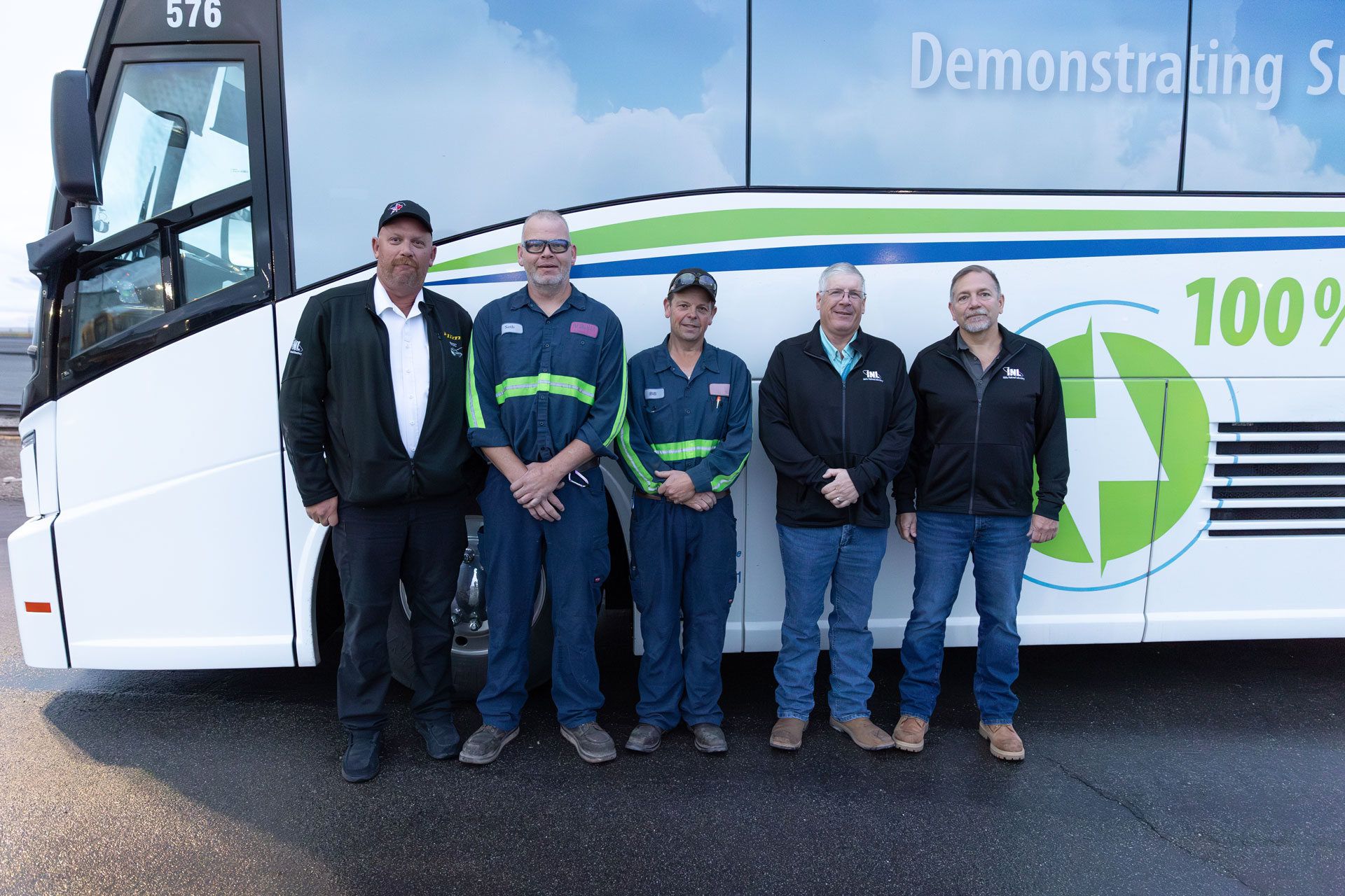 5 men standing in front of INL bus