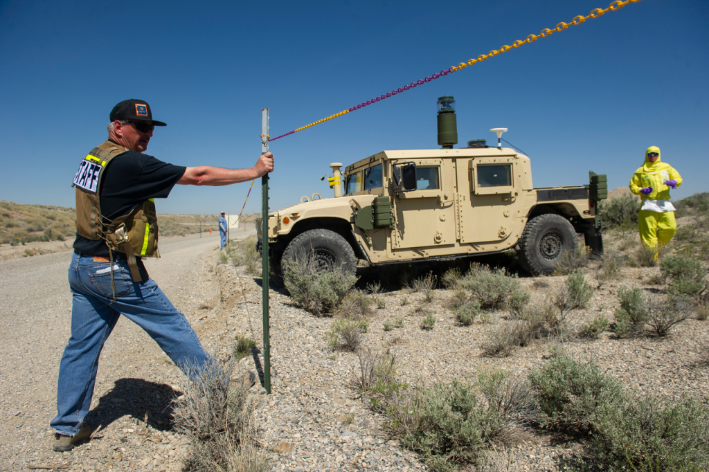 man in hazmat suit next to military jeep in the desert