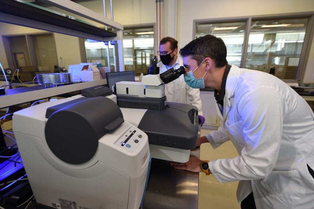 scientist looking into microscope at the Pyrochemistry Laboratories