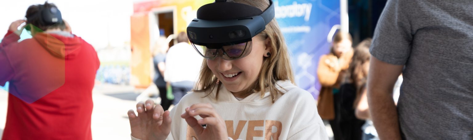 Girl smiling while using a mixed reality headset during a STEM activity.