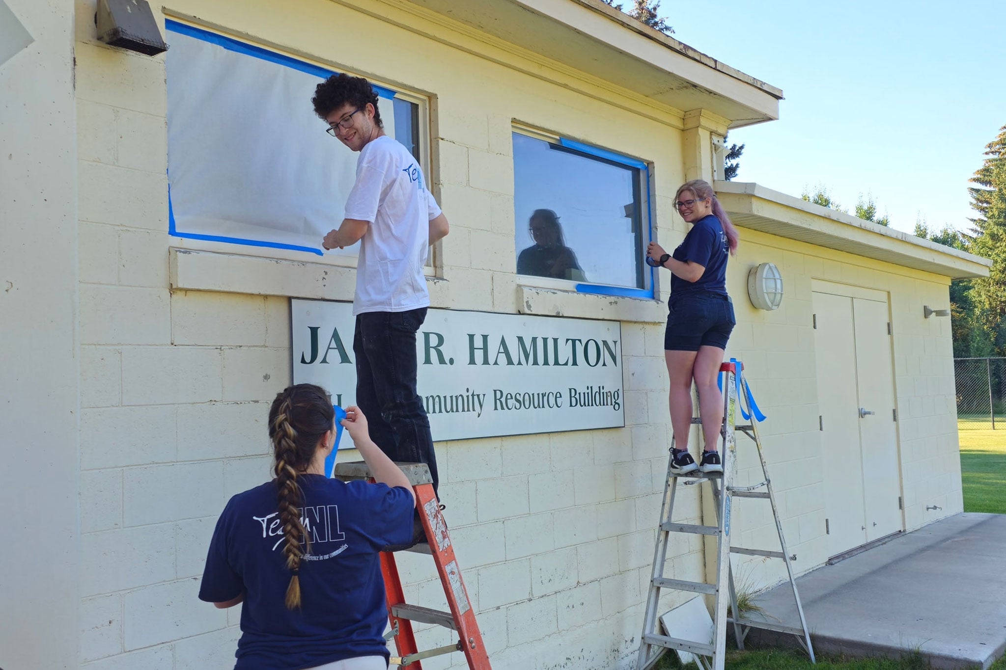 INL volunteers painting the outside of a community center