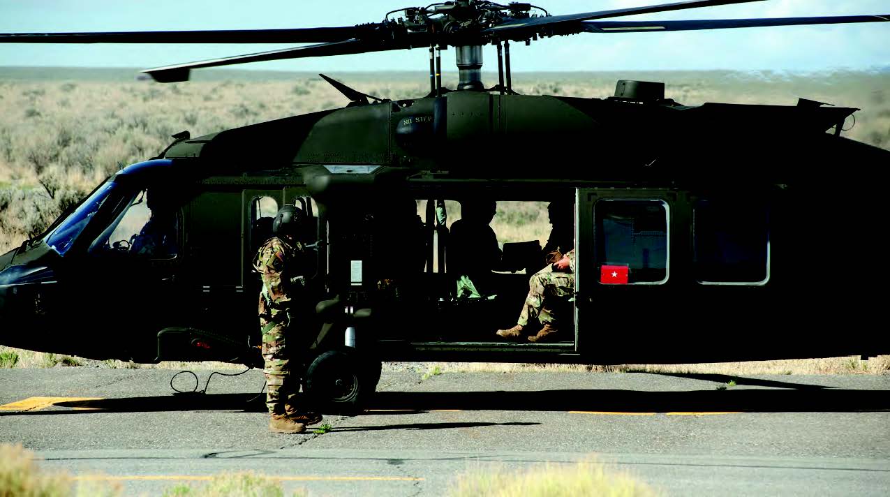 Military helicopter on the ground with uniformed personnel boarding and seated inside.