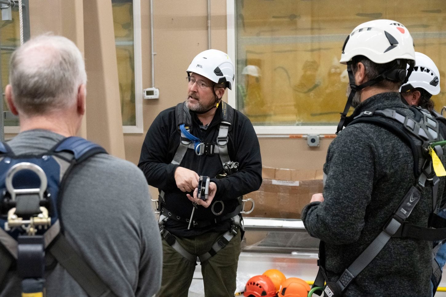 Instructor wearing safety gear talking with others.