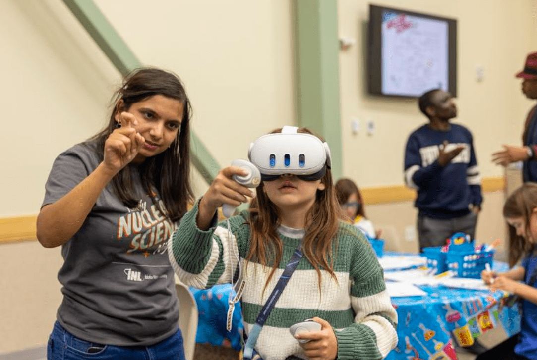 Student using a VR headset with guidance from an instructor during a STEM activity.