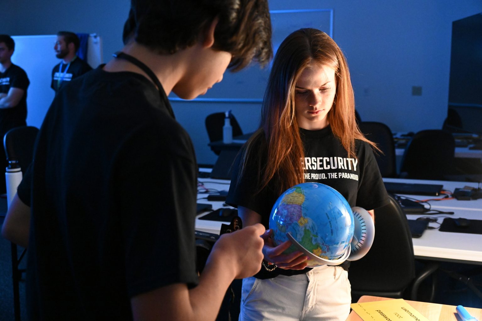 Students examining a globe during a cybersecurity-themed classroom activity.