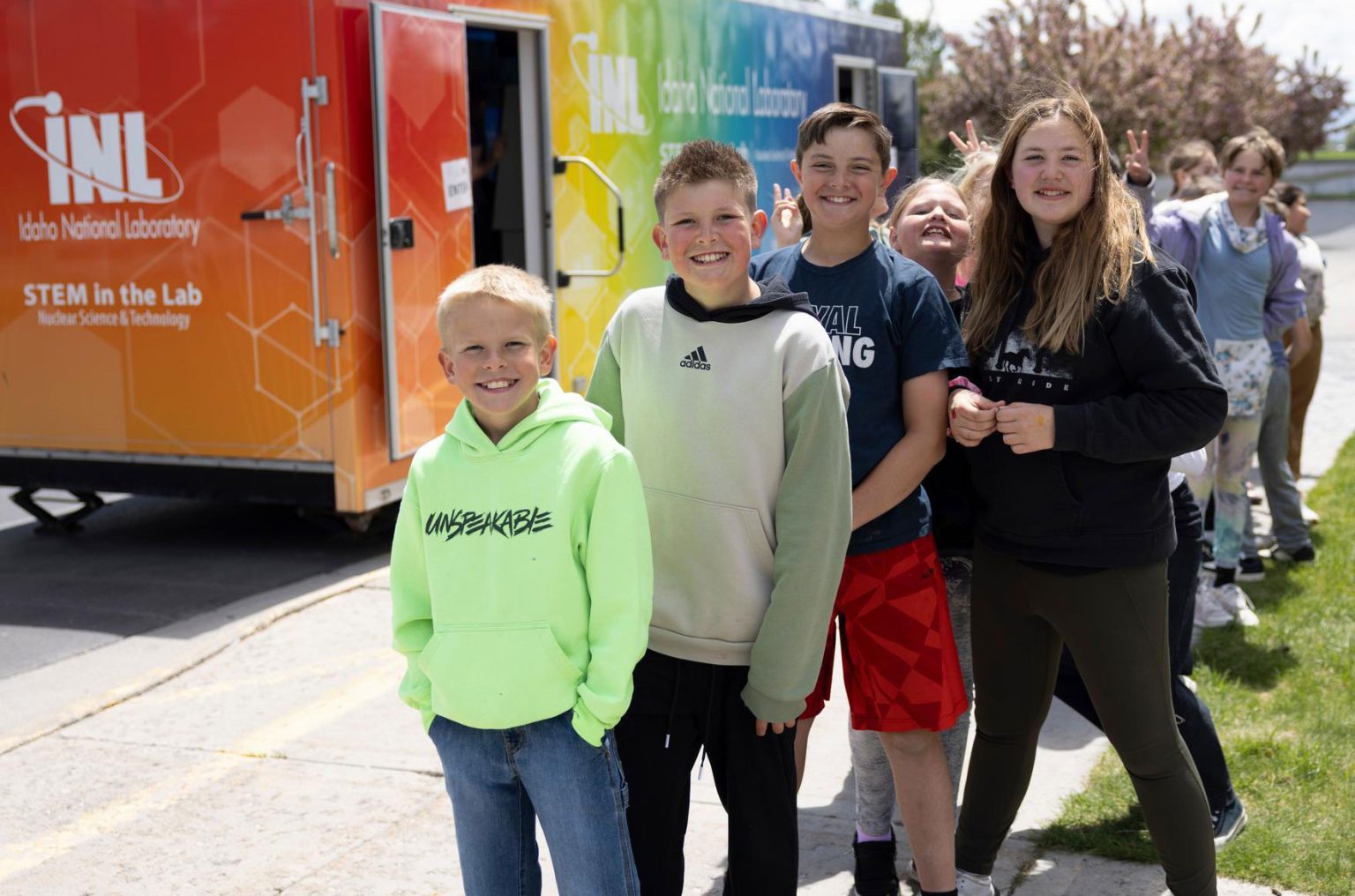 Group of smiling kids standing outside an INL STEM outreach trailer.
