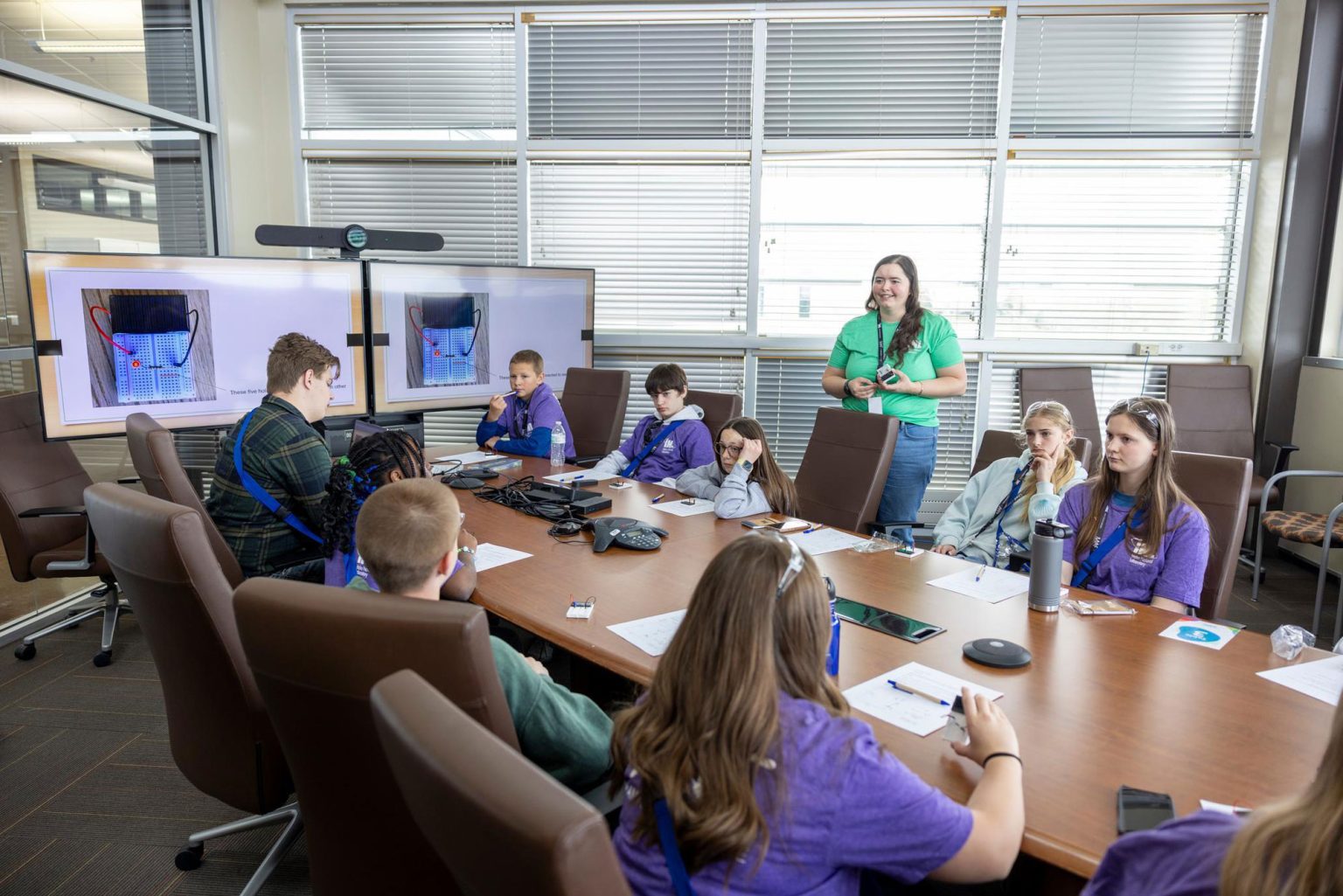 Students gathered around a conference table participating in a hands-on STEM workshop.