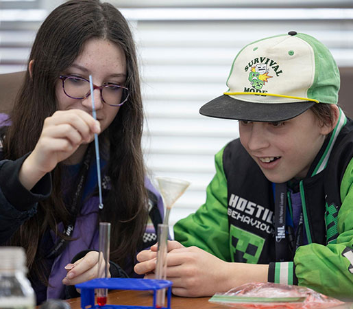 Two kids using droppers and test tubes during a hands-on science experiment.