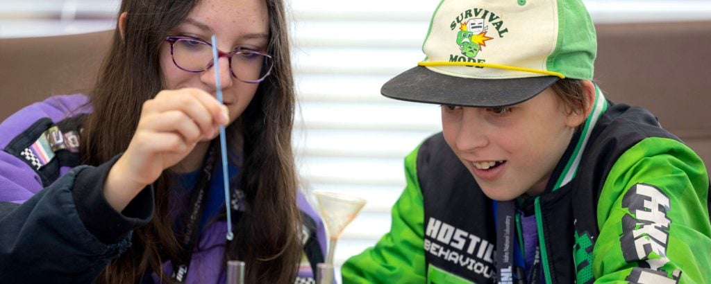 Two students conducting a hands-on experiment using droppers and lab tools.