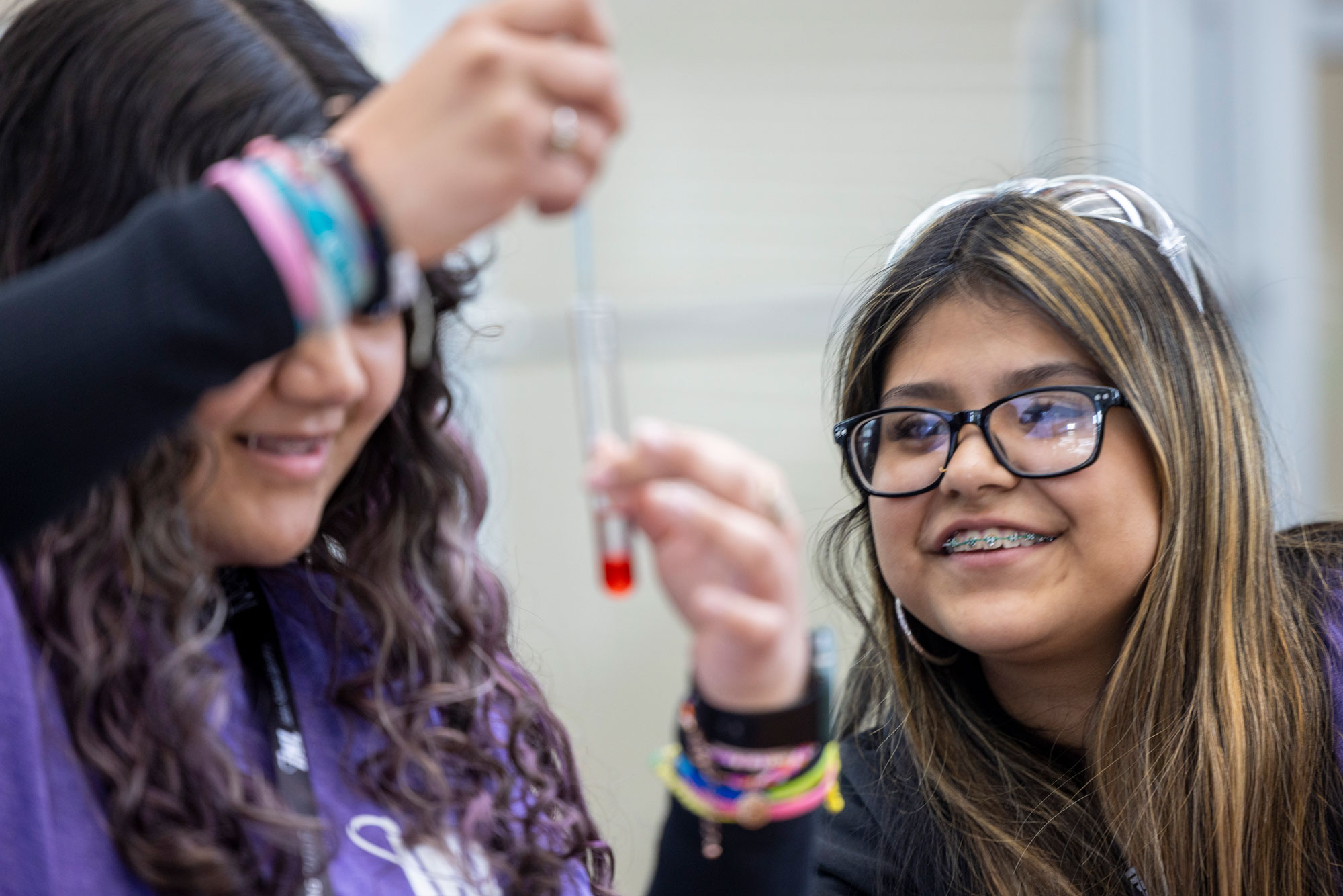Two students smiling while examining a test tube during a science experiment.
