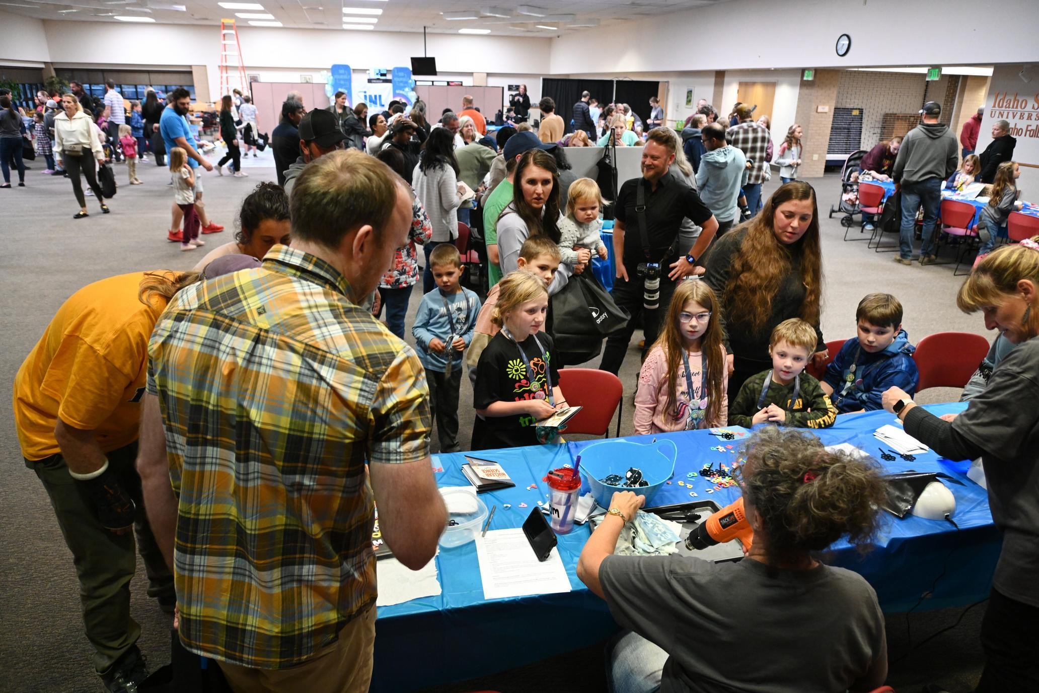 Families participate in hands-on STEM activities at a crowded community science event.
