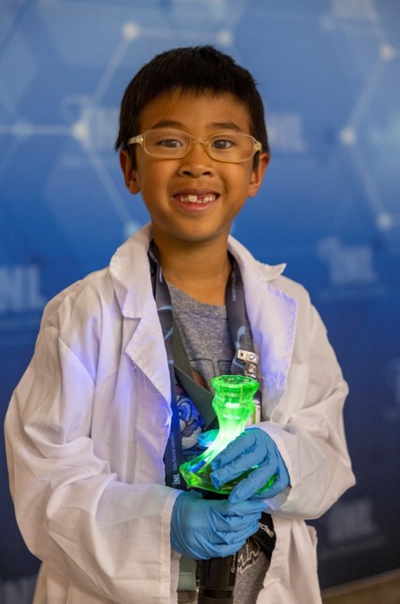 An attendee is dressed as a scientist holds a glowing beaker during the event.