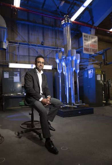 Yasir Arafat with the PCAT prototype in the background, fabricated at the Materials and Fuels Complex Fabrication Shop.